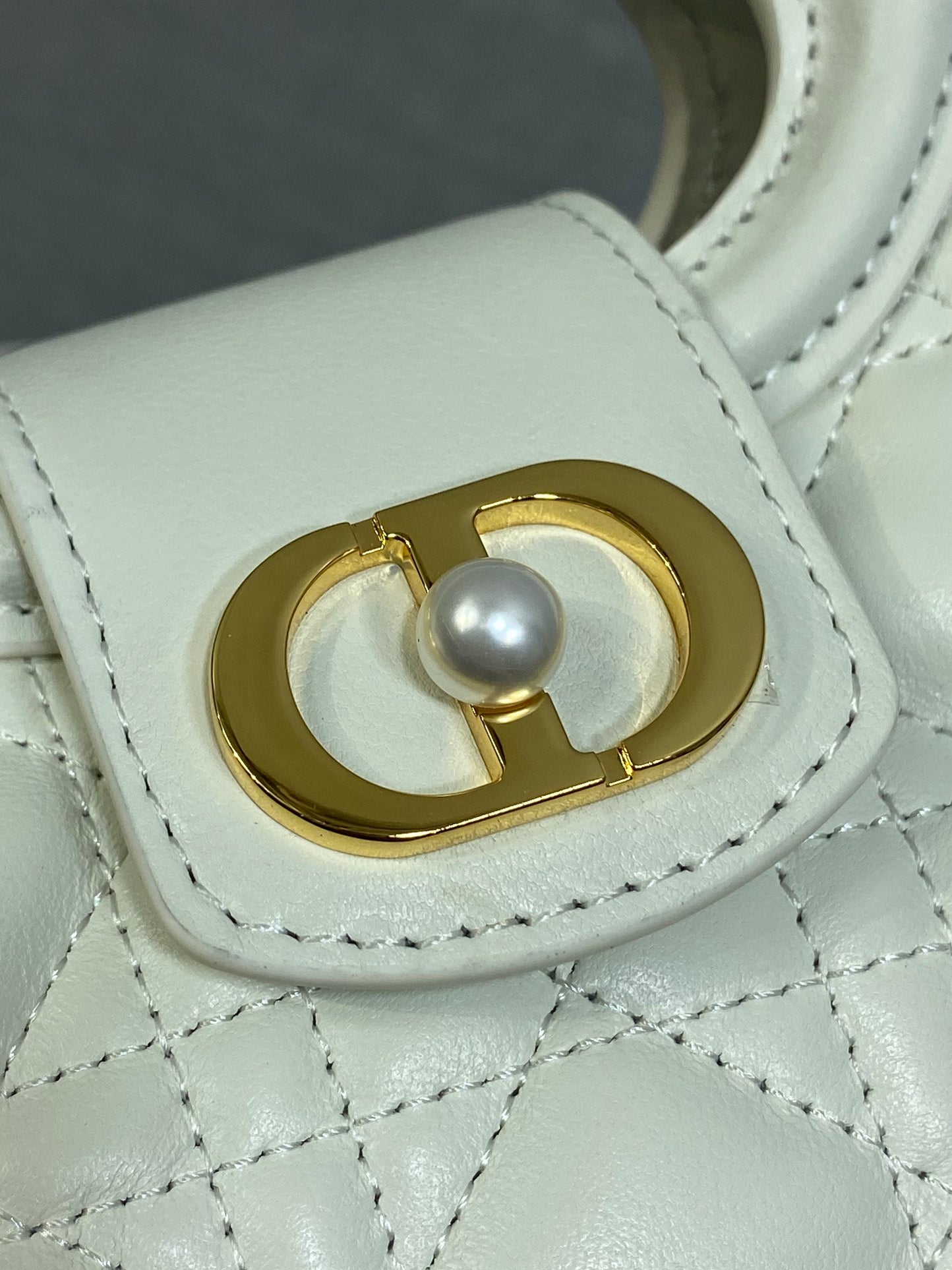 Dior quilted mini handbag close-up of gold clasp with pearl accent and stitching