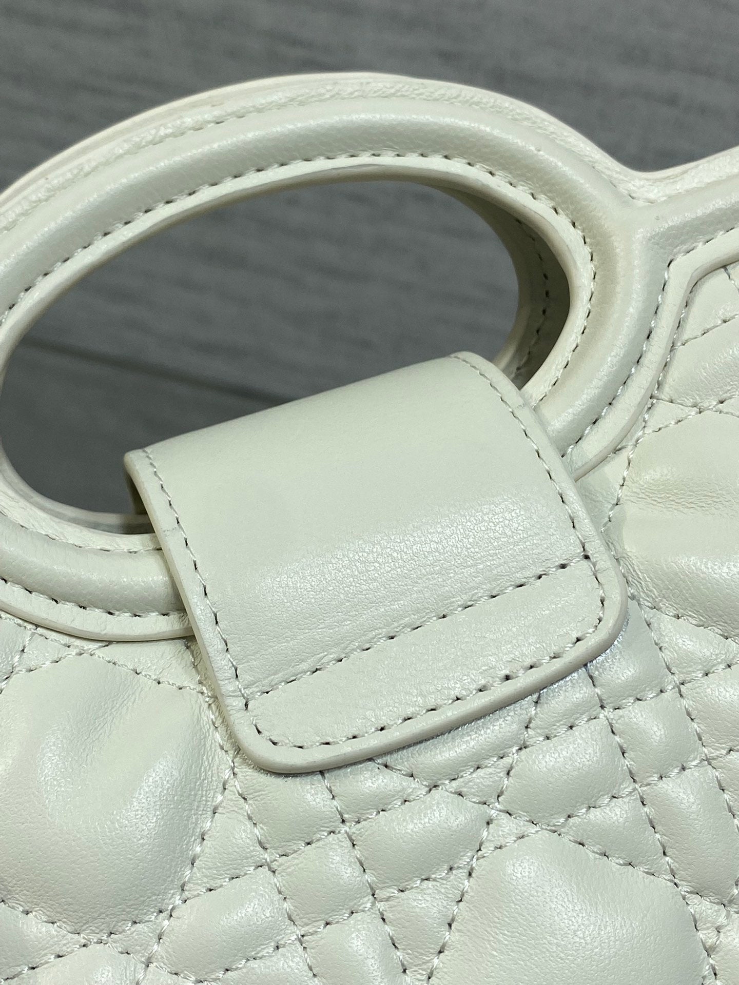 Dior quilted mini handbag close-up of top handle and strap attachment tab