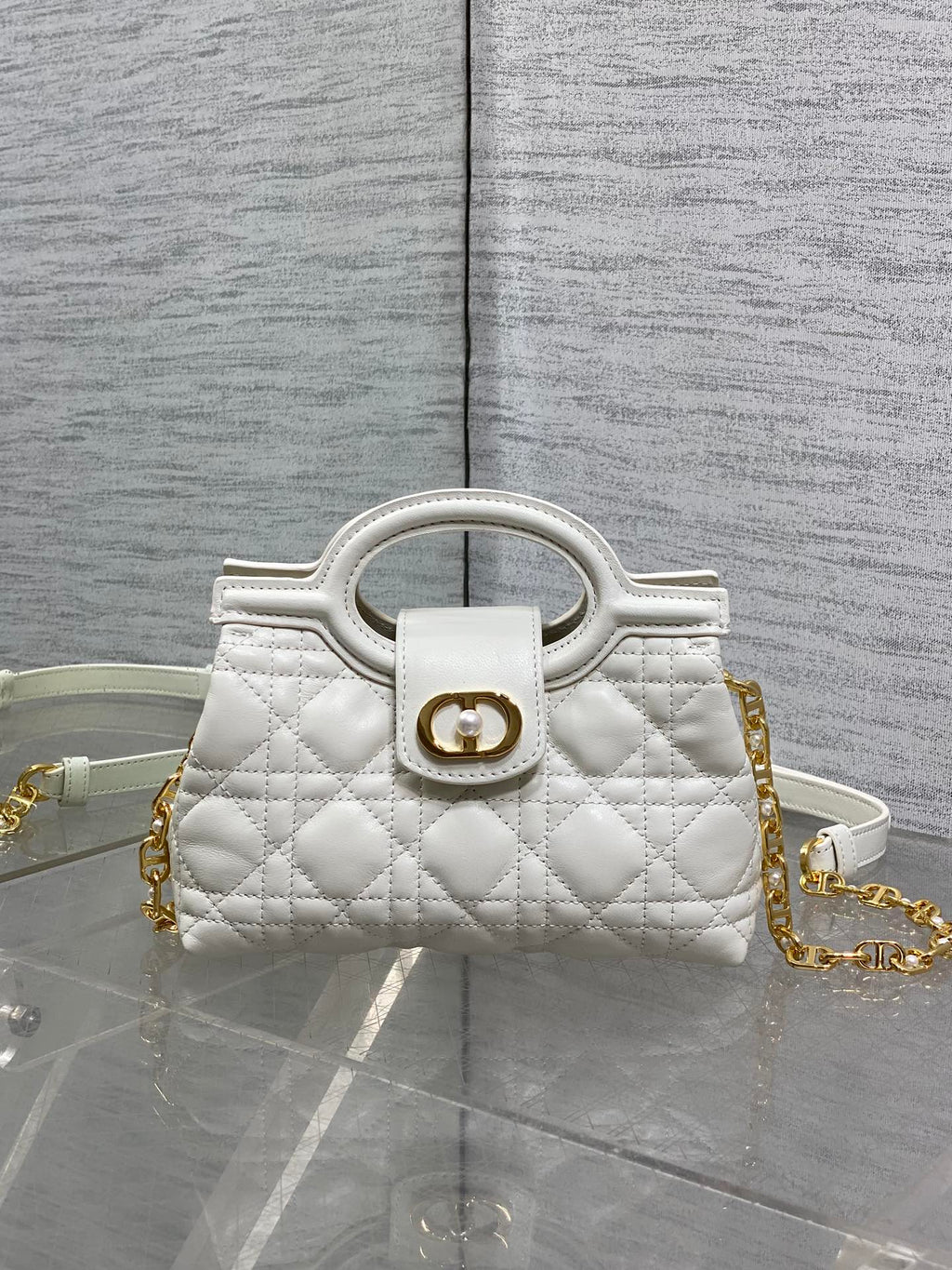 Dior quilted mini handbag with top handle, gold emblem clasp, and chain strap