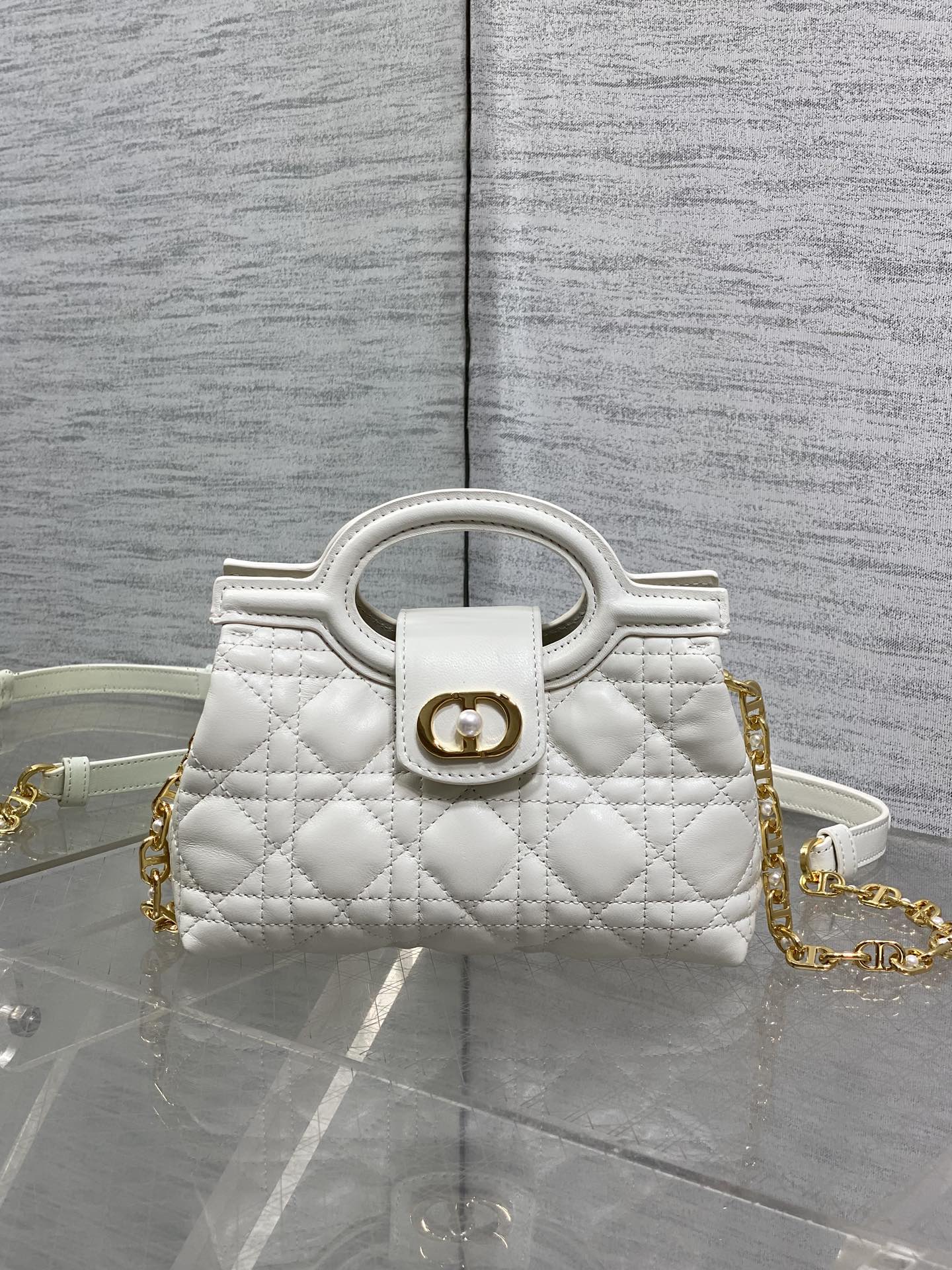 Dior quilted mini handbag with top handle, gold emblem clasp, and chain strap
