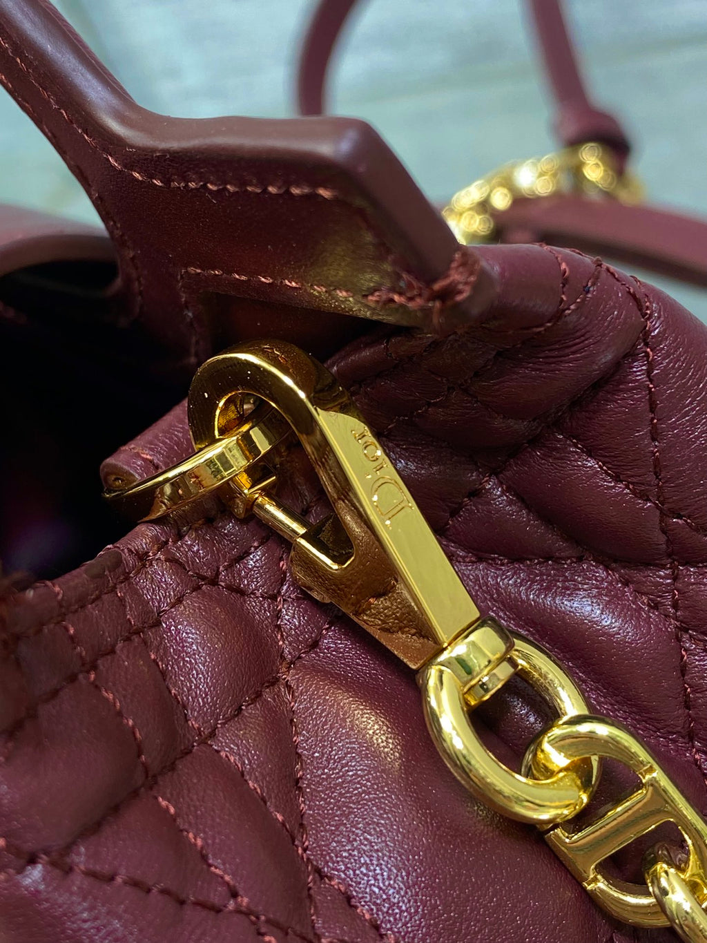 Maroon quilted handbag closure with gold-tone latch and gold chain strap