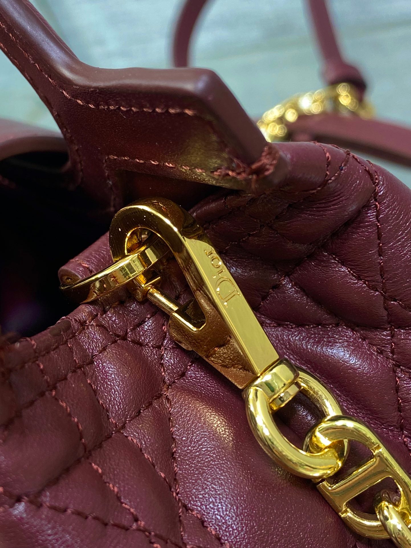 Maroon quilted handbag closure with gold-tone latch and gold chain strap