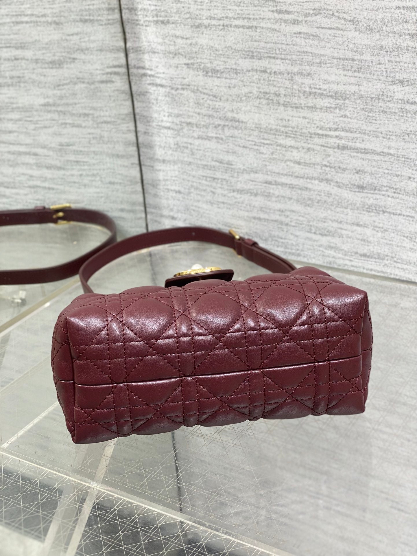 Maroon quilted handbag with rounded top, short handle, and gold-tone hardware