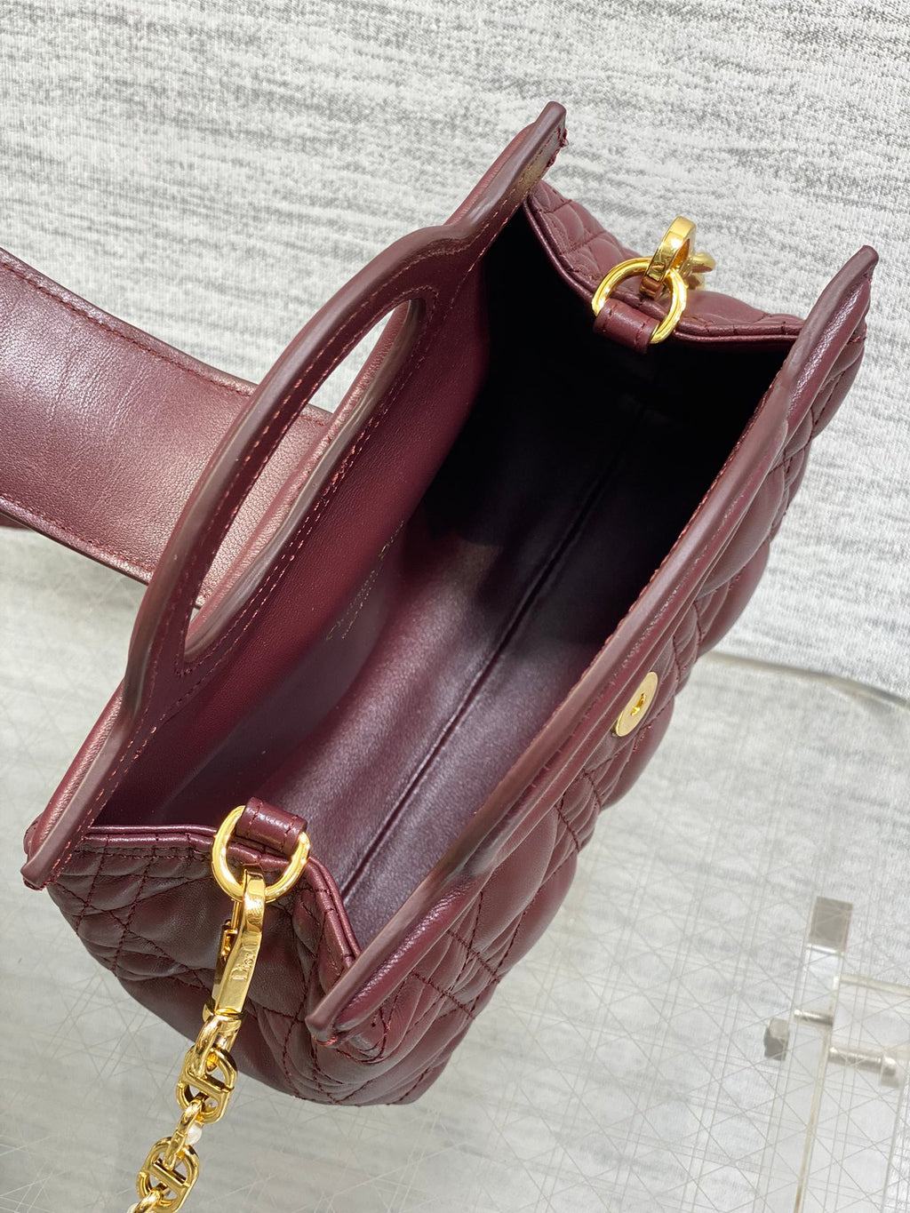Open maroon quilted handbag with interior lining and gold chain shoulder strap
