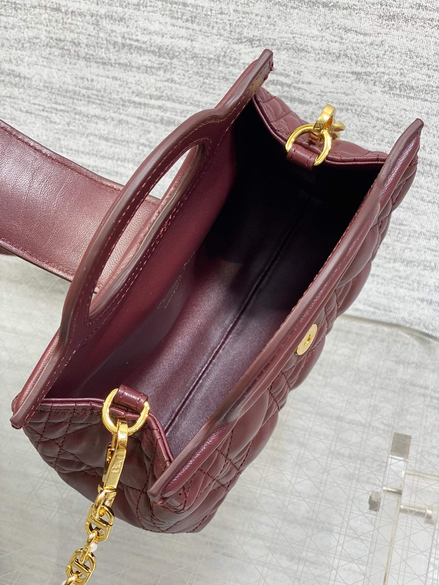 Open maroon quilted handbag with interior lining and gold chain shoulder strap