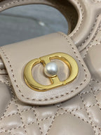 Beige quilted handbag detail with gold ring clasp and pearl charm
