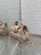 Beige quilted mini handbag with top handle and gold chain strap, side view
