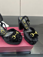 Close view of Gucci women’s black heeled mules with gold buckle accent and block heel