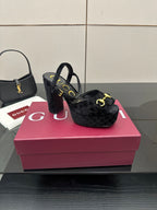 Gucci women’s black heeled mules with gold buckle accents and open-toe design