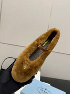 Women's tan suede flat with logo emblem, interior lining visible