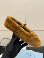 Women's tan suede flat with buckle strap and emblem close-up