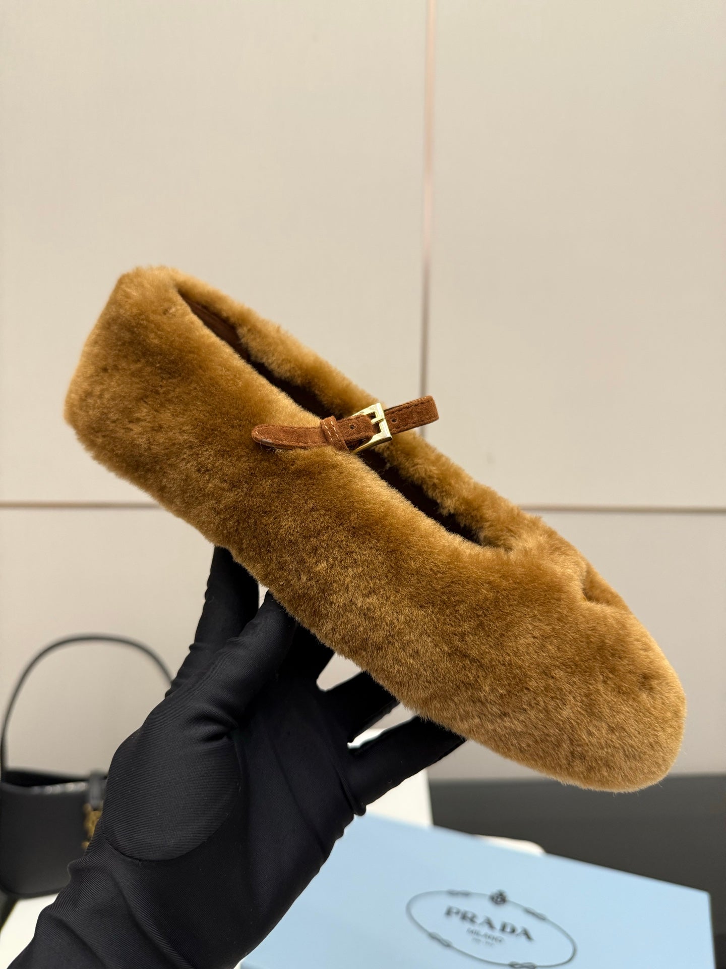 Women's tan suede flat with buckle strap and emblem close-up