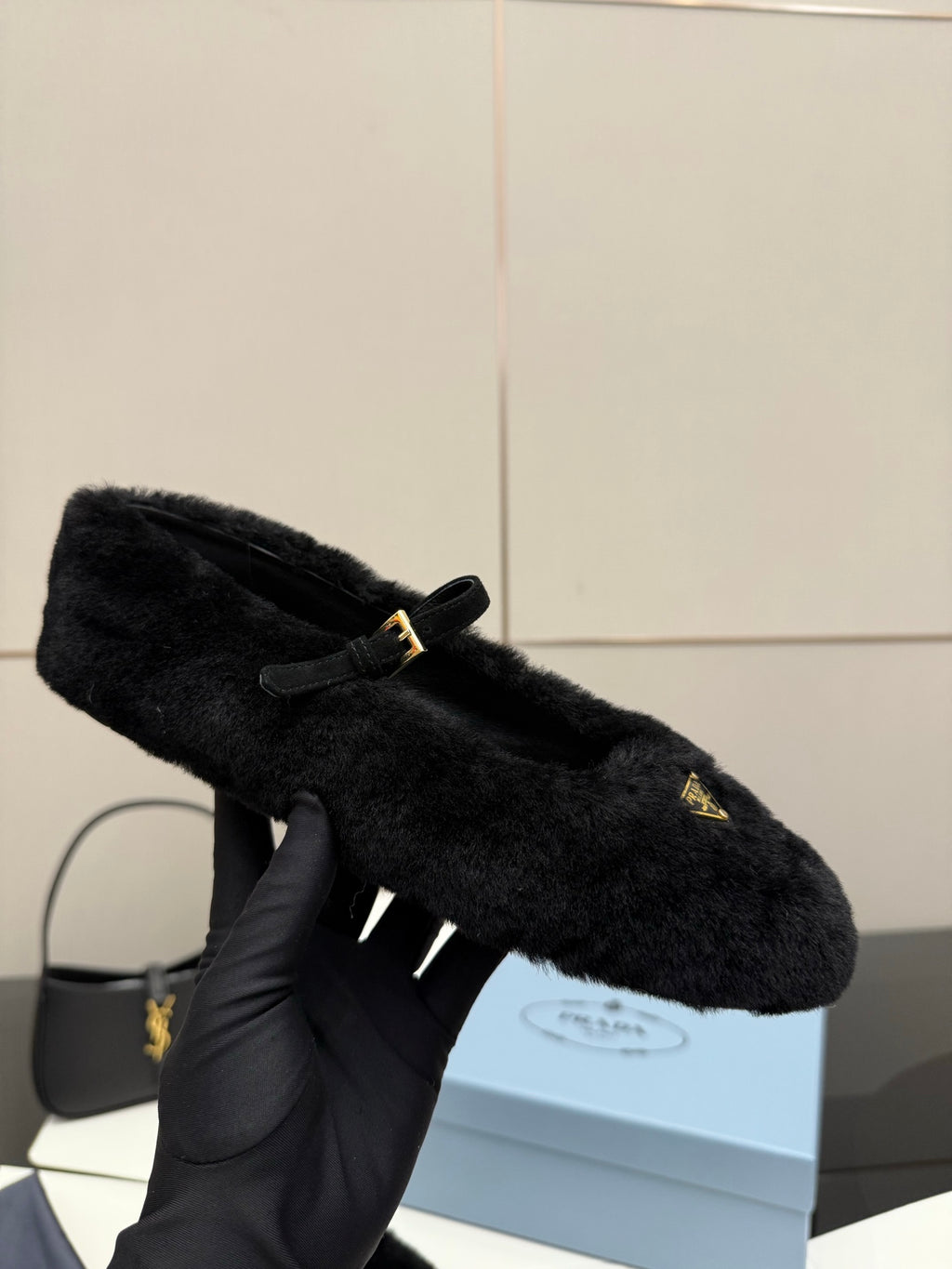 Prada women's black plush loafer held up, gold logo triangle detail