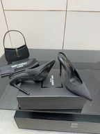 Women’s stiletto heeled pumps, dark leather, pair shown on display box