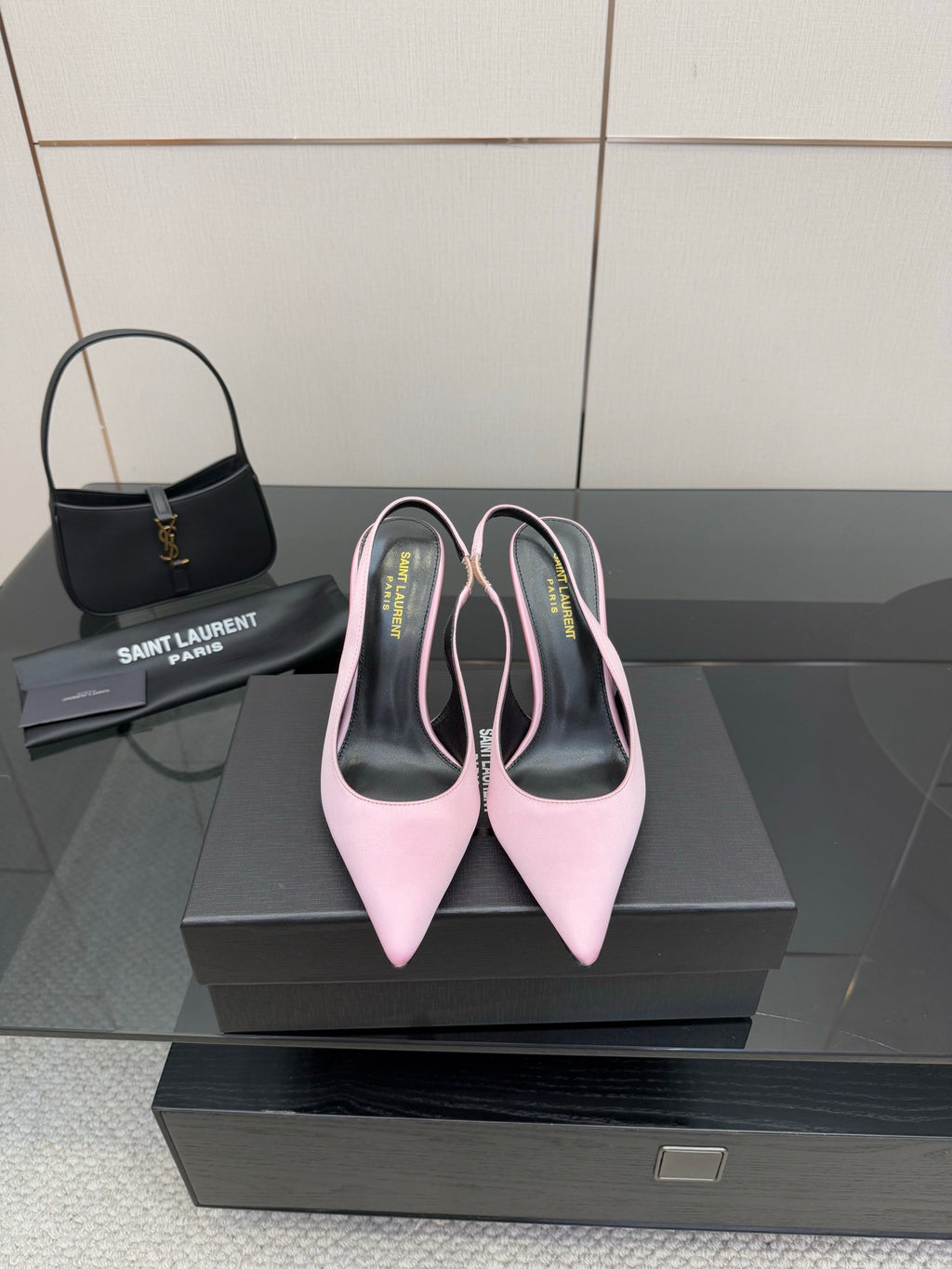 Pink pointed-toe stiletto heels, pair on black shoebox with heel tips visible