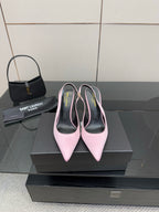 Pink pointed-toe stiletto heels, pair on black shoebox with heel tips visible