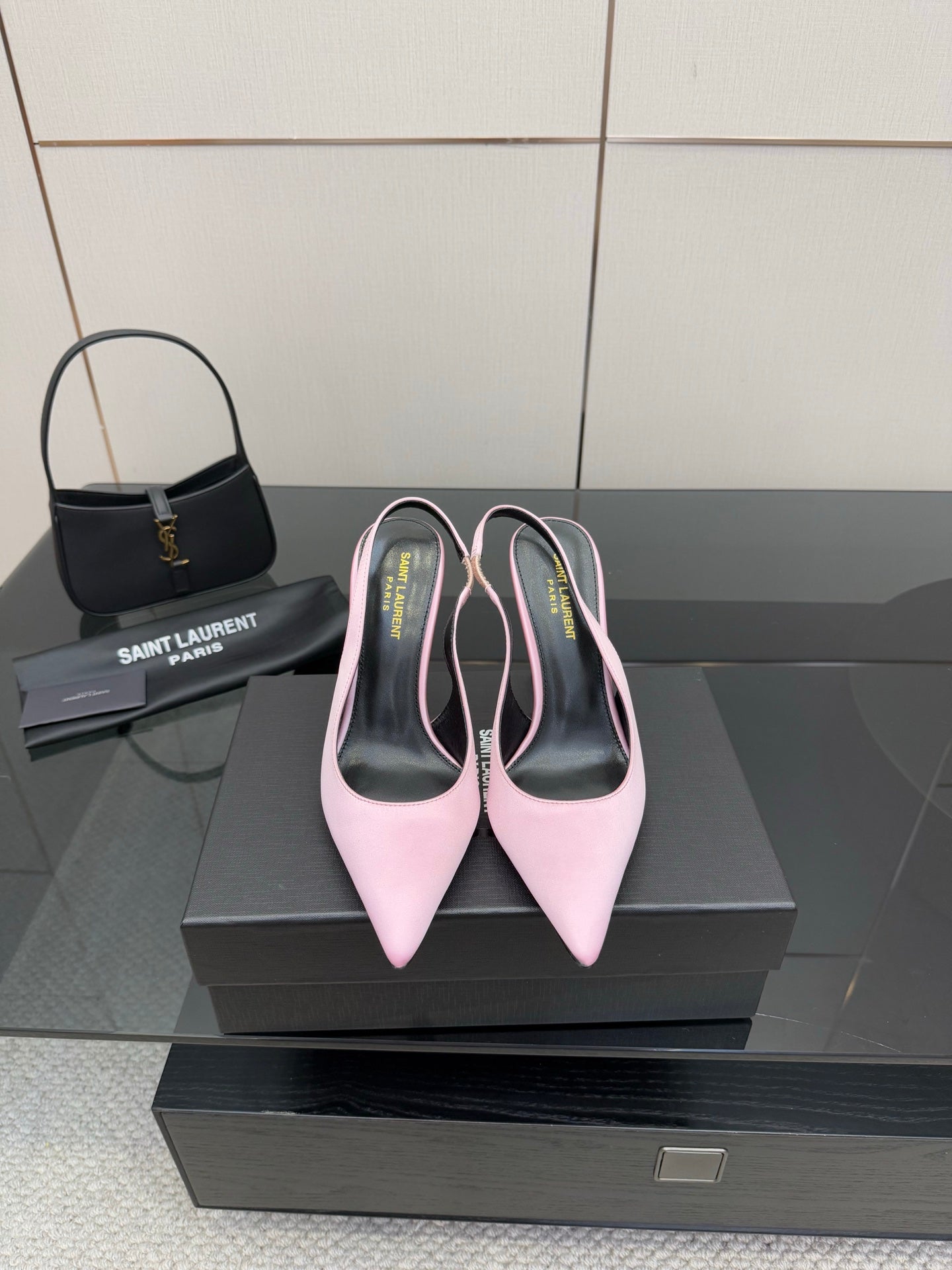 Pink pointed-toe stiletto heels, pair on black shoebox with heel tips visible