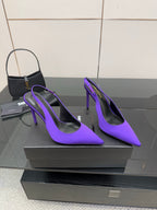 Purple pointed-toe stiletto pumps, angled front view on a display pedestal.