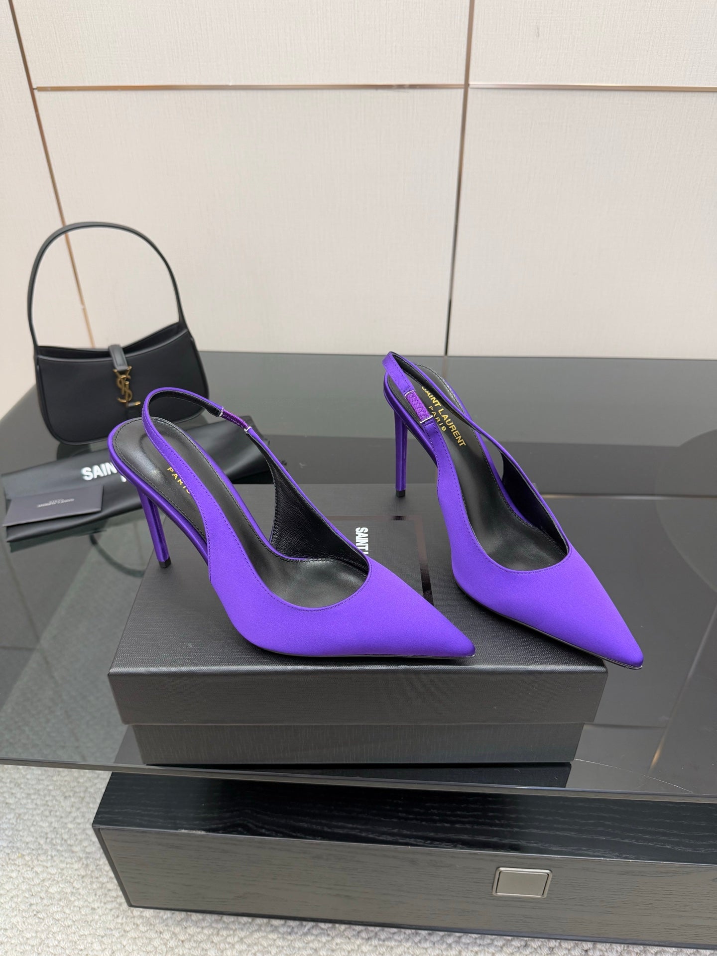 Purple pointed-toe stiletto pumps, angled front view on a display pedestal.