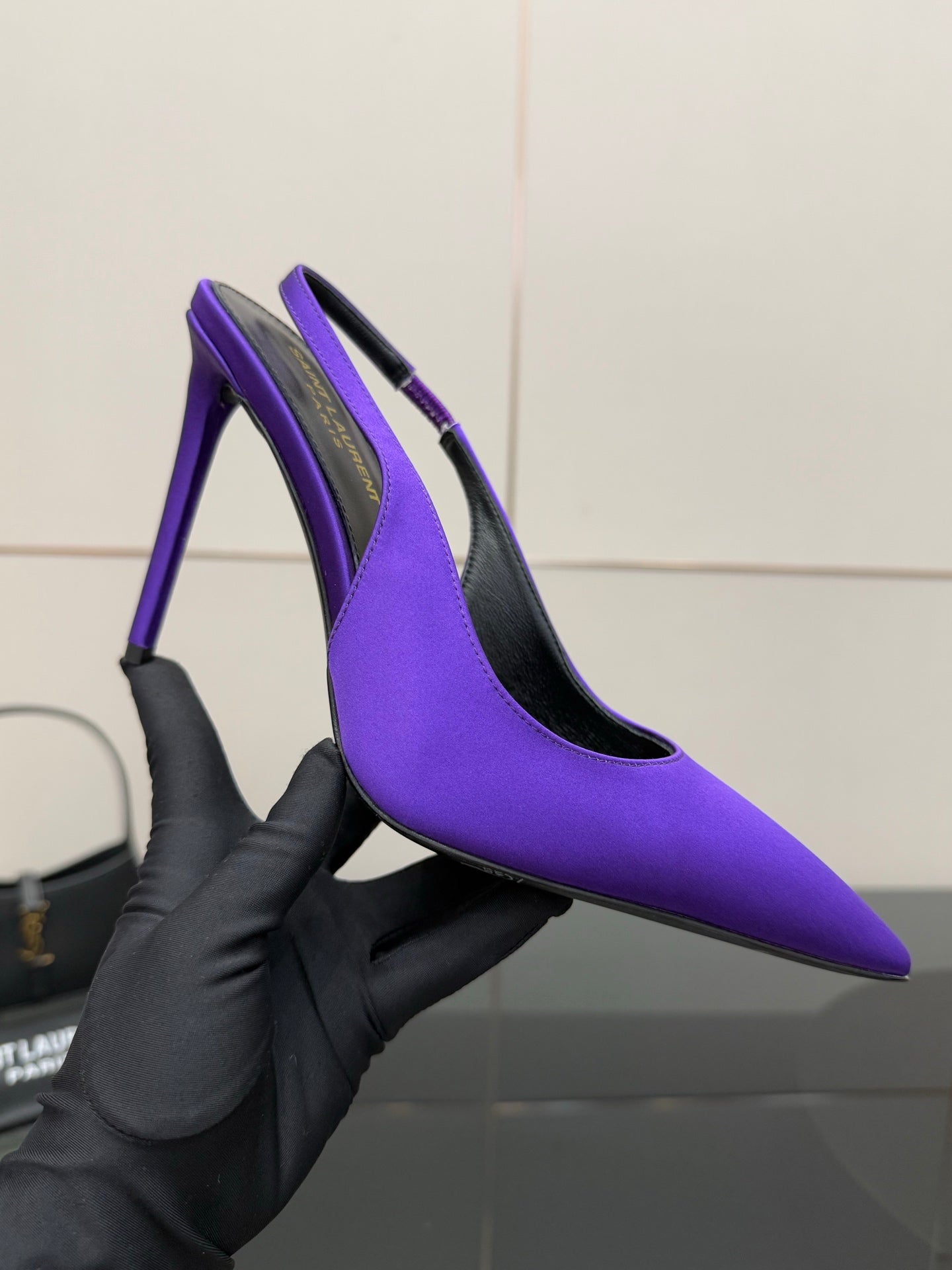 Purple pointed-toe stiletto pump on hand, showing black inner lining.