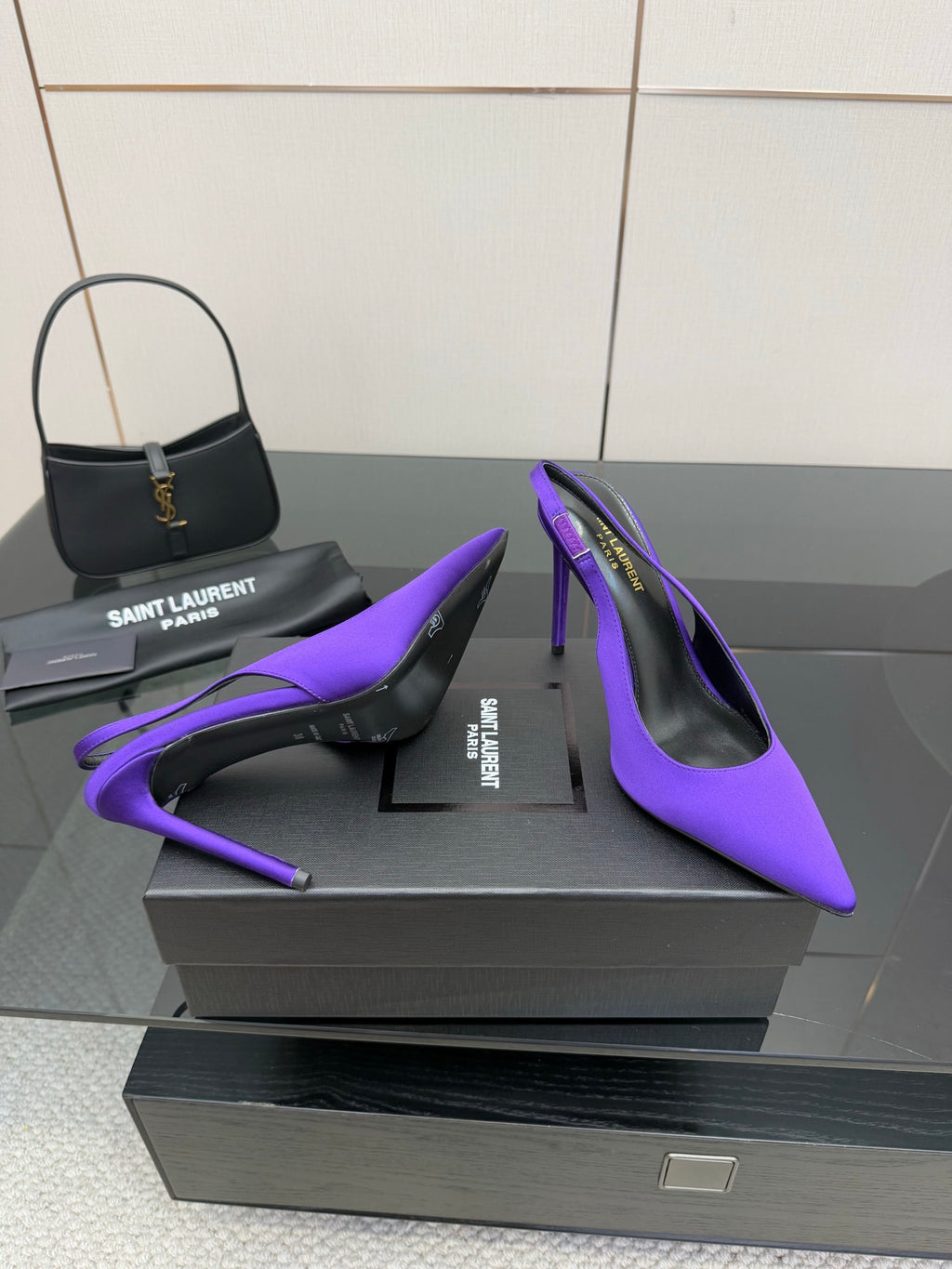 Purple pointed-toe stiletto pumps, overlapping toe and heel detail on box.