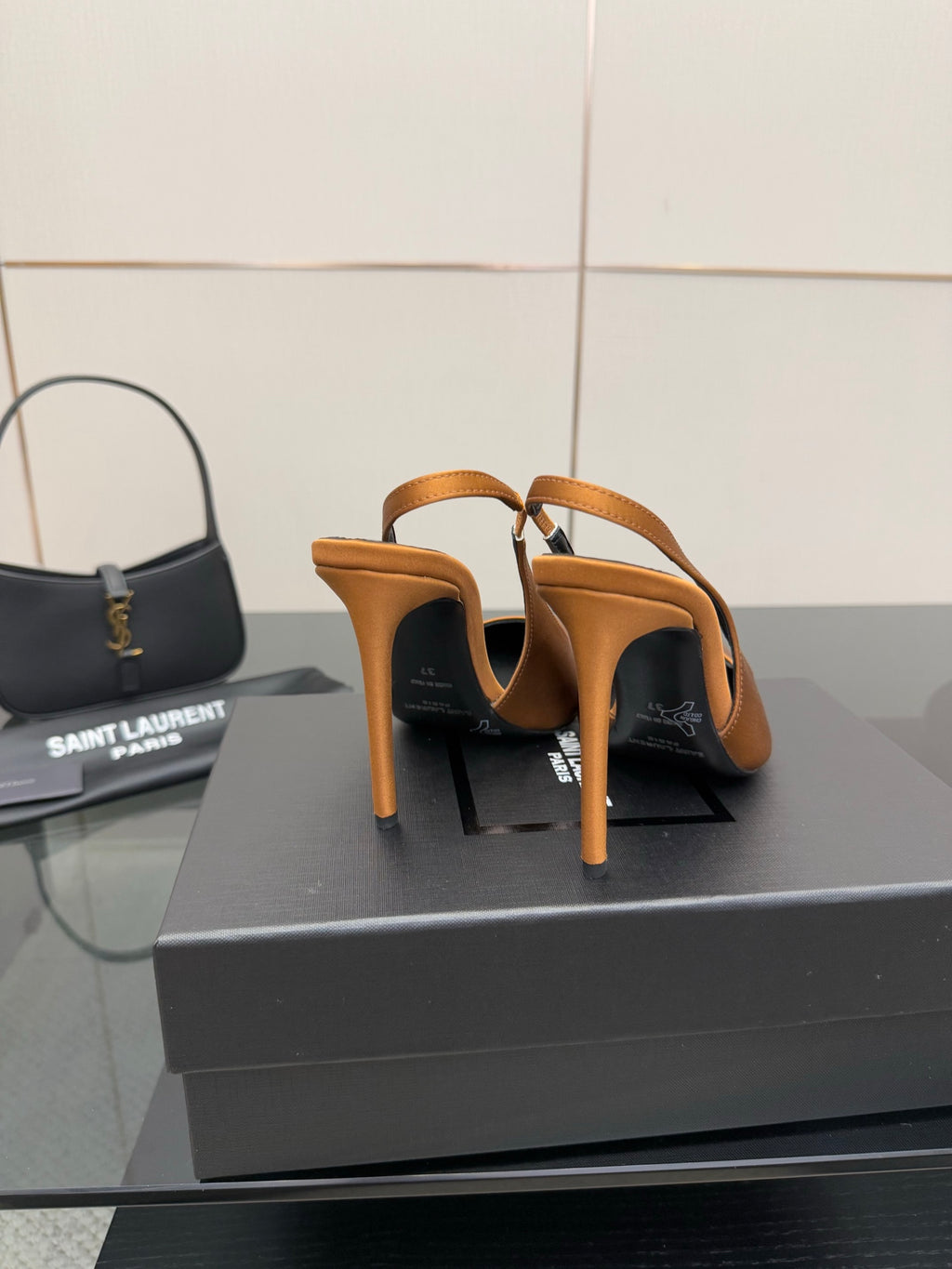 Orange high-heel pumps viewed from behind, showing open heel and back stitching