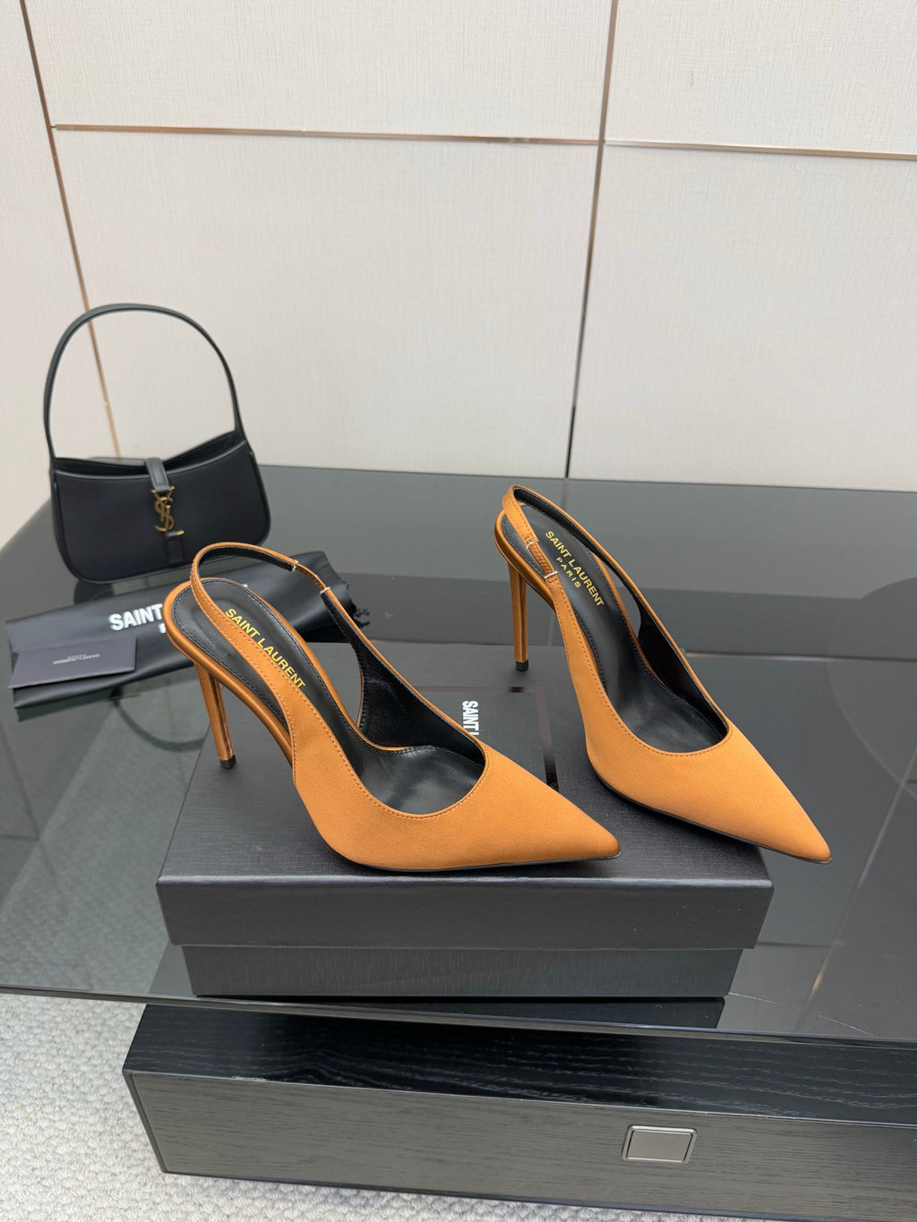 Pair of orange pointed-toe high-heel pumps on a black display box