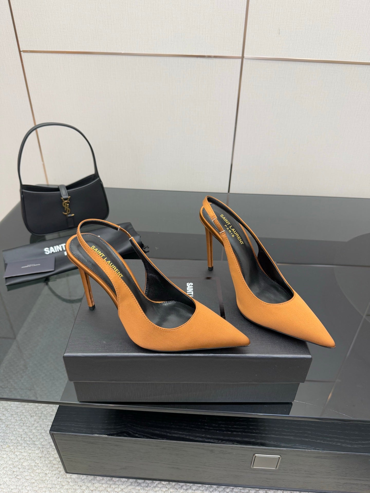 Pair of orange pointed-toe high-heel pumps on a black display box