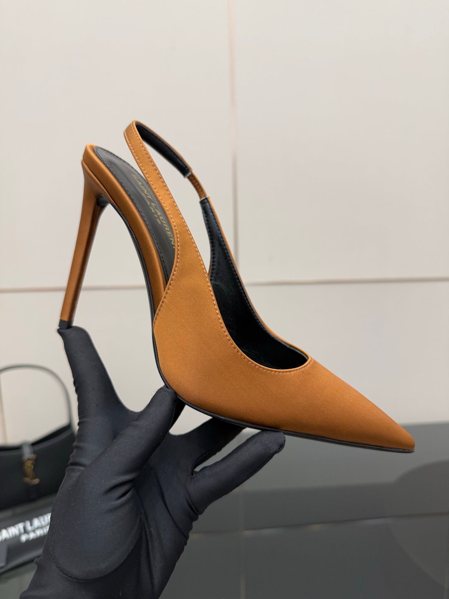Orange pointed-toe high-heel pump held near sole and stiletto heel