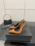 Orange pointed-toe high-heel pumps displayed on black shoe boxes