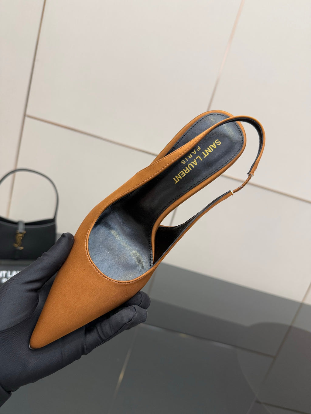 Orange pointed-toe high-heel pump held open, showing branded insole