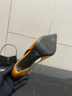 Yellow pointed-toe stiletto pump heel shown close-up with black sole detailing
