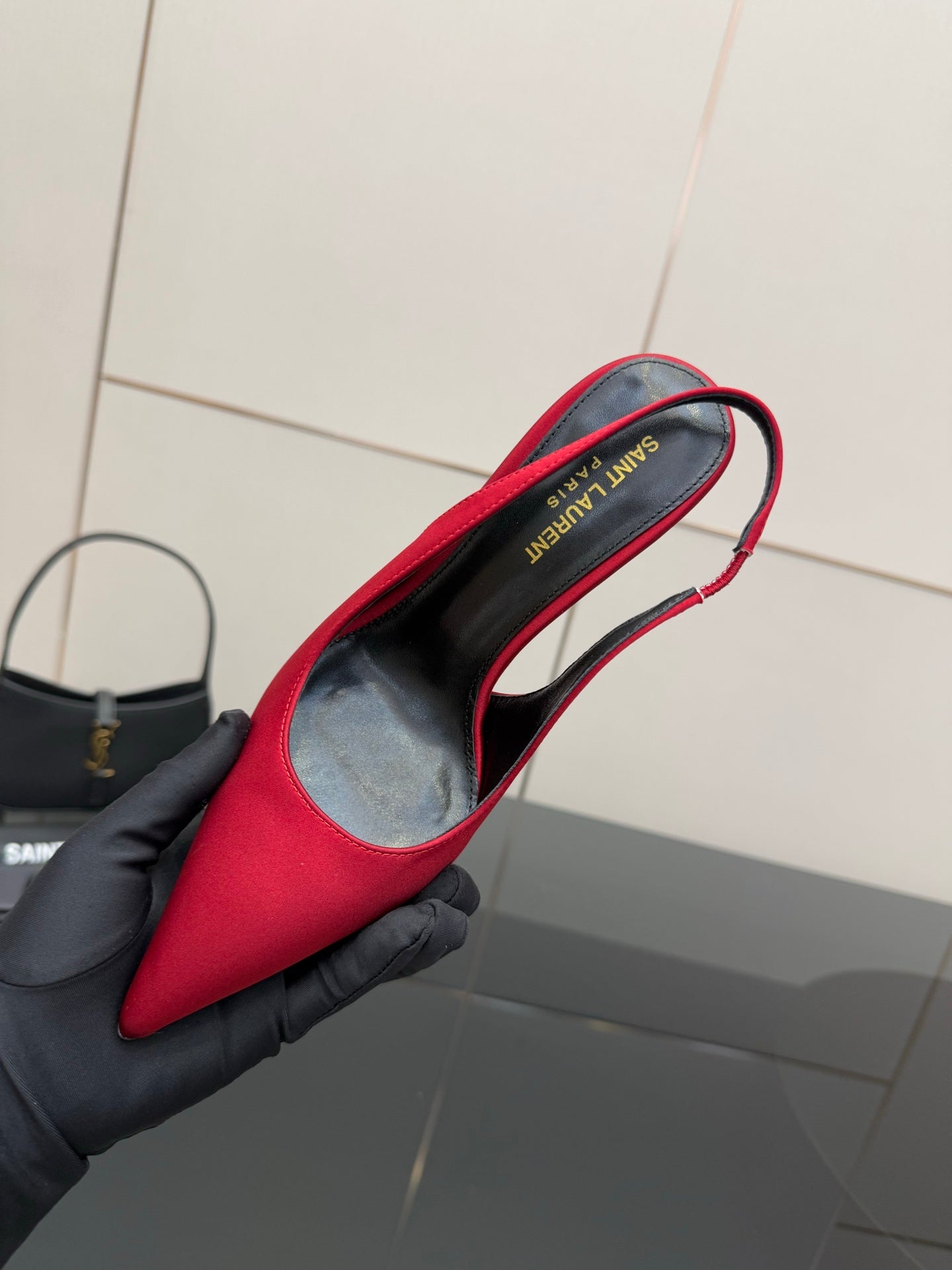 Ladies red high-heel pumps held in black glove, showing inner side