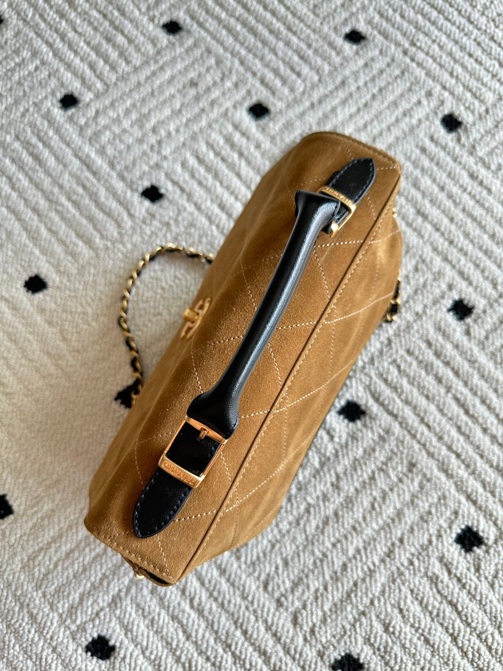 Designer handbag in tan with gold chain and black top handle with logo clasp