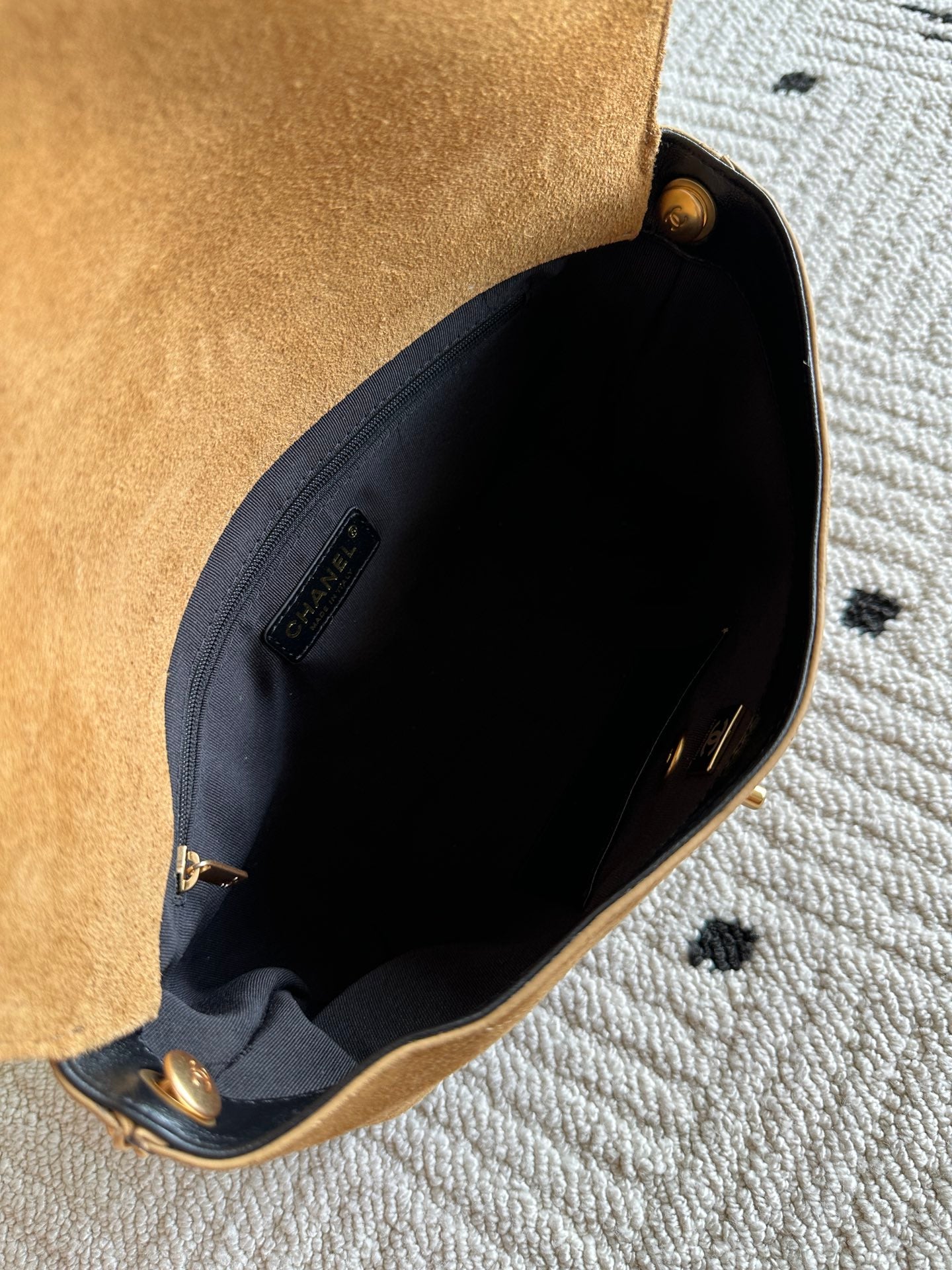 Designer bag opening with tan suede trim and black fabric interior