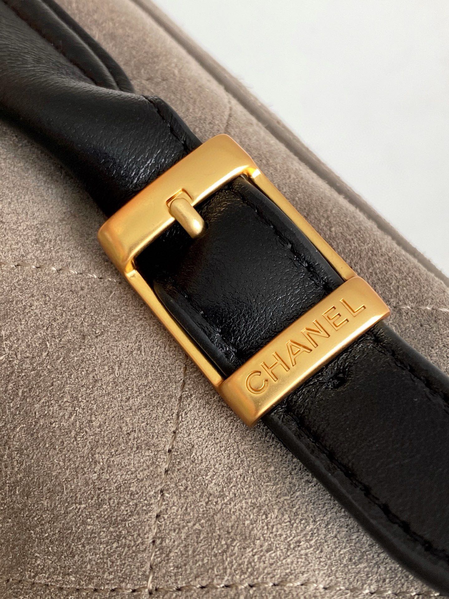 Chanel bag close-up of gold buckle with black strap and CHANEL logo