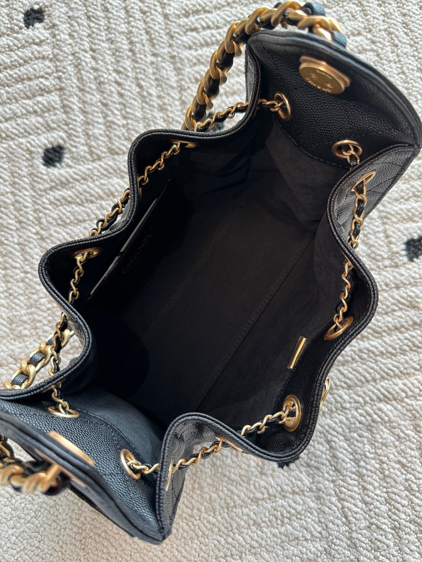 Chanel bag interior view, open black leather bucket with gold chain strap