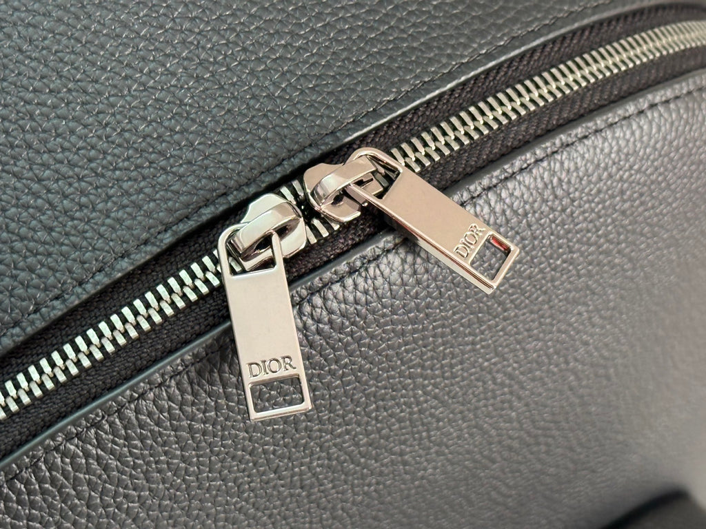 Close-up of silver-tone zipper and metal zipper tags on dark green bag.