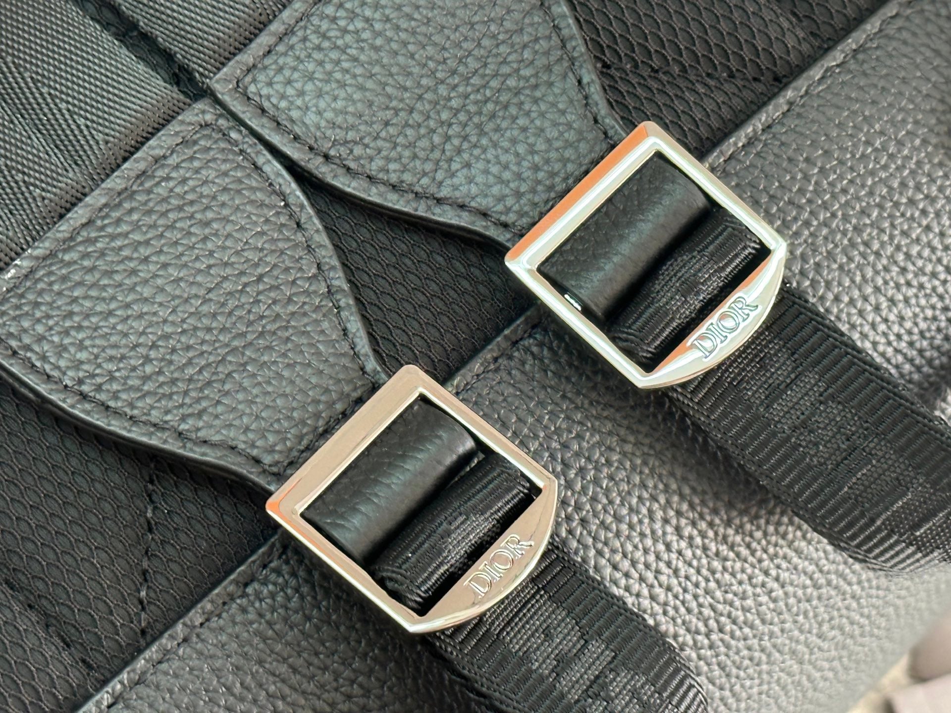 Close-up of dark green adjustable strap buckle with gold-tone frame and logo label.
