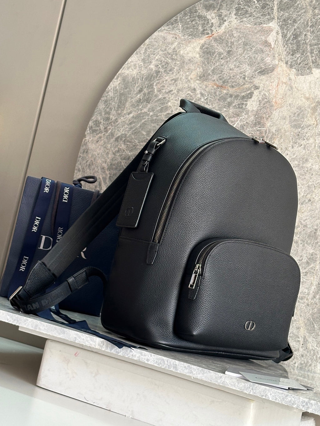 Dark green leather-look backpack with side straps and front zip pocket.