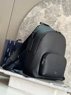 Dark green leather-look backpack with side straps and front zip pocket.
