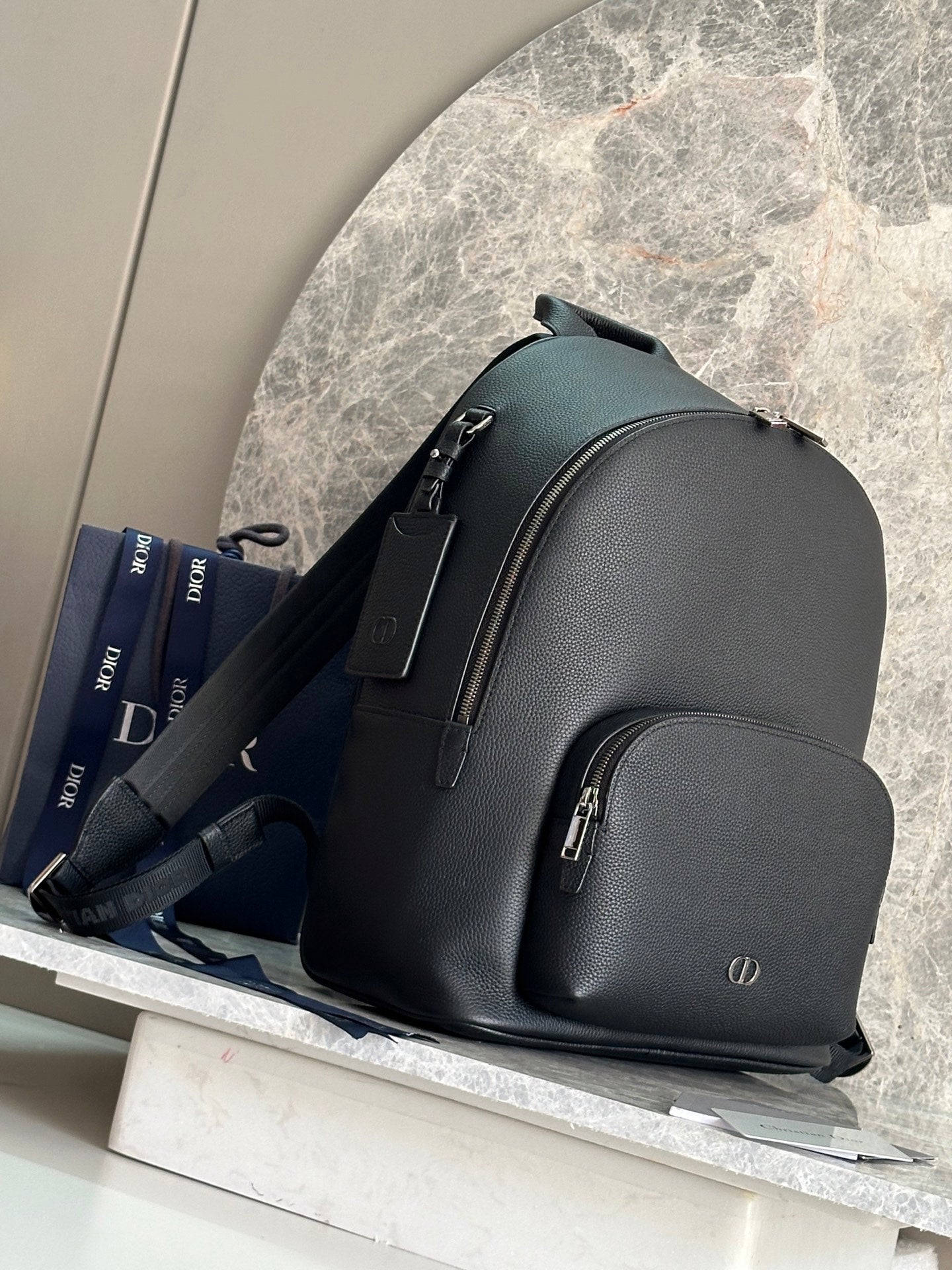 Dark green leather-look backpack with side straps and front zip pocket.