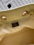 Pale yellow handbag exterior with gold-tone turn-lock hardware and logo patch.