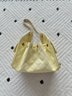 Bucket-style handbag in pale yellow with quilted sides and gold chain handles.