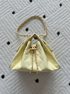 Chanel bag in pale yellow with quilted fabric and gold chain top handle.