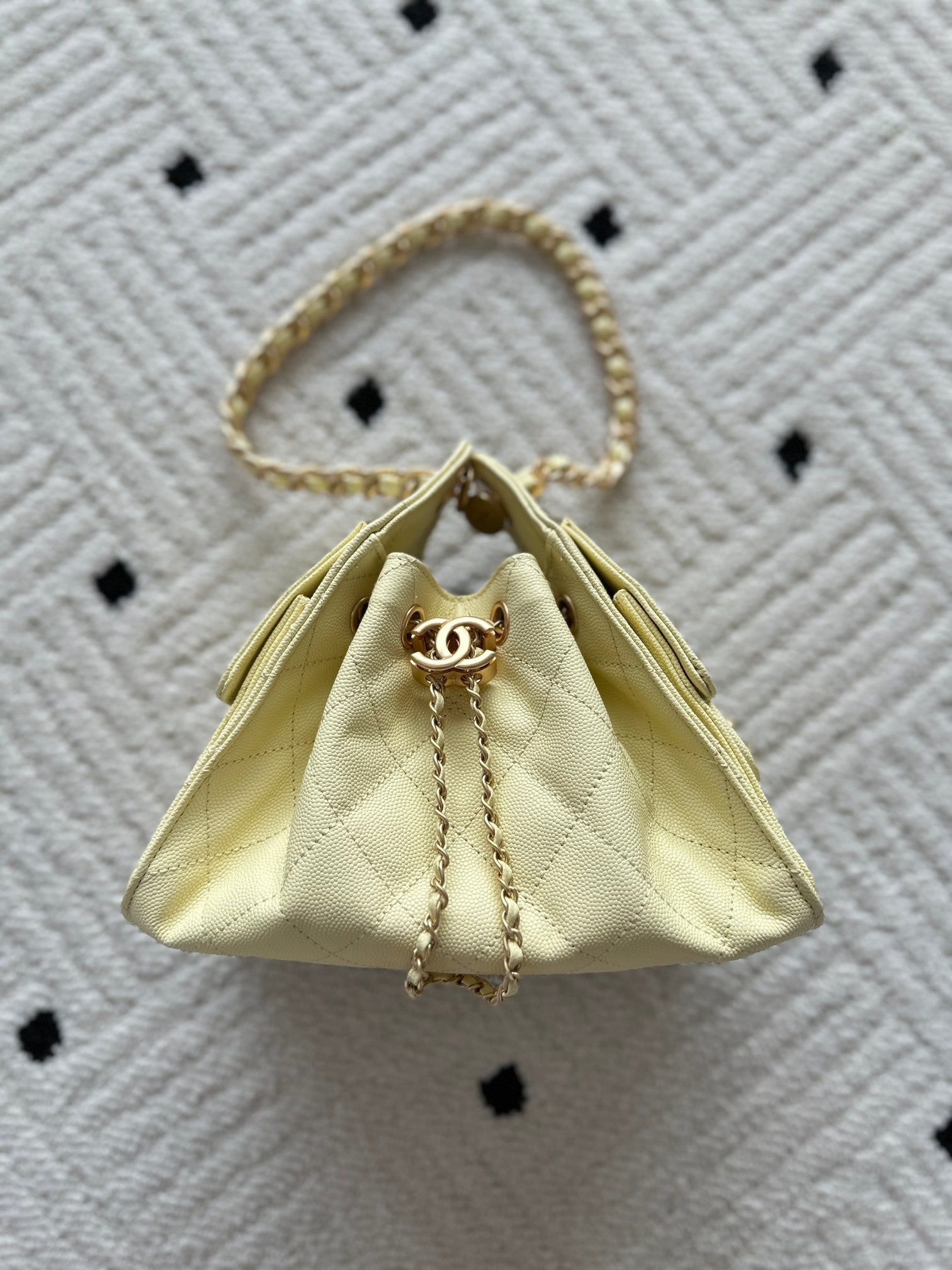 Chanel bag in pale yellow with quilted fabric and gold chain top handle.