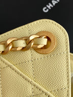 Pale yellow leather bag with circular gold logo medallion and chain link.