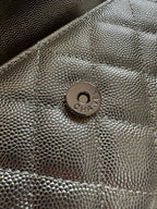Chanel bag front logo medallion on textured metallic surface