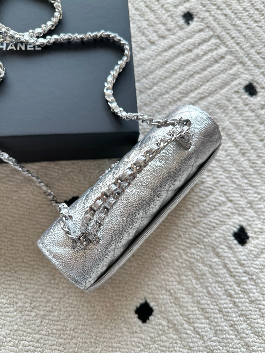 Light silver quilted flap bag with chain strap and small logo hardware on flap