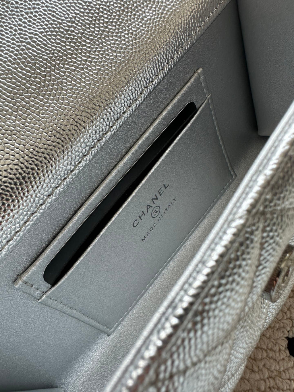 Light silver bag interior card slot with Chanel text branding on divider